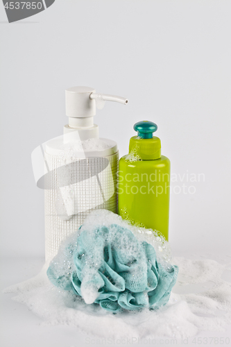 Image of Bath cosmetic products, green sponge and foam on light backgroun