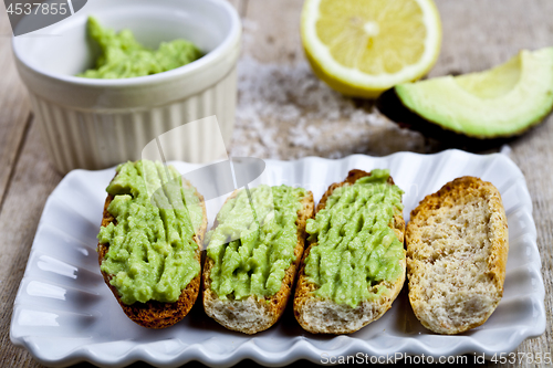 Image of Fresh crostini with avocado guacamole on white plate closeup on 