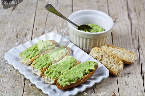 Image of Crostini with avocado guacamole on white plate closeup on rustic