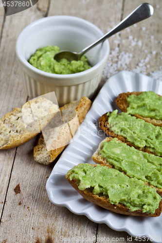 Image of Croutons with avocado guacamole on white plate closeup on rustic