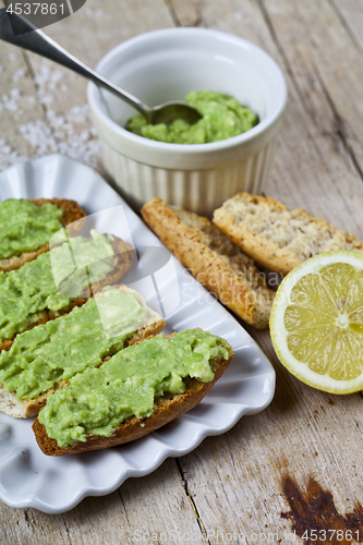 Image of Toasts with avocado guacamole on white plate closeup on rustic w