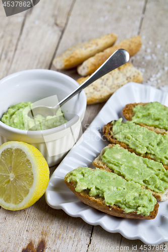 Image of Toasts with avocado guacamole on white plate closeup on rustic w