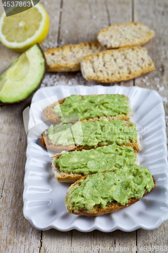 Image of Fresh crostini with avocado guacamole on white plate closeup on 