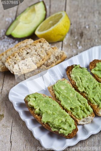 Image of Fresh crostini with avocado guacamole on white plate closeup on 