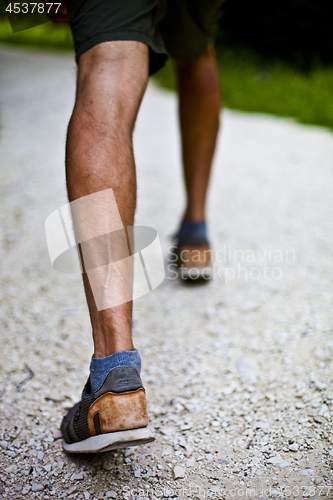 Image of Low angle ground level view with feet of a man on park or forest