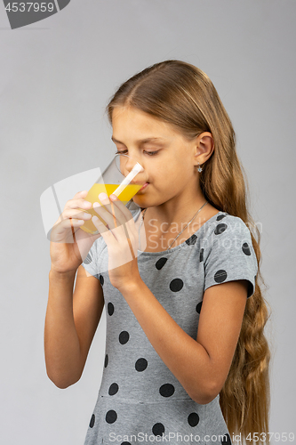 Image of A ten-year-old girl drinks juice, half-sided view