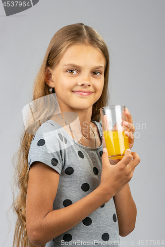 Image of The girl proudly holds a glass of juice