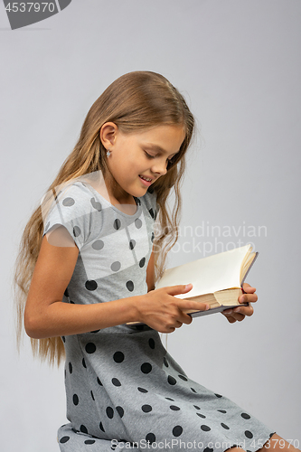 Image of A ten years old girl enjoys reading a book
