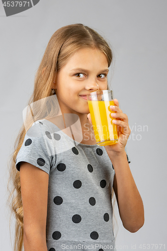 Image of A ten-year-old girl drinks juice, and with a smile looked at the frame