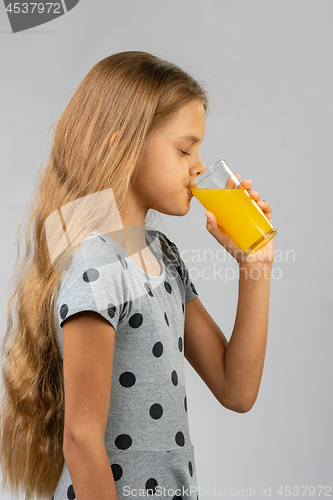 Image of Ten-year girl drinks juice, profile view