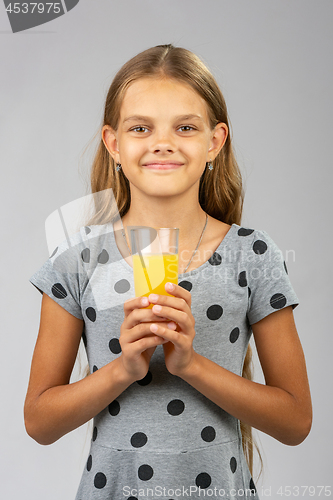 Image of A girl holds a glass of juice in her hands with both hands