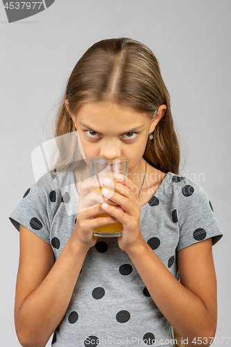 Image of A ten year old girl drinks juice and enjoys the scent