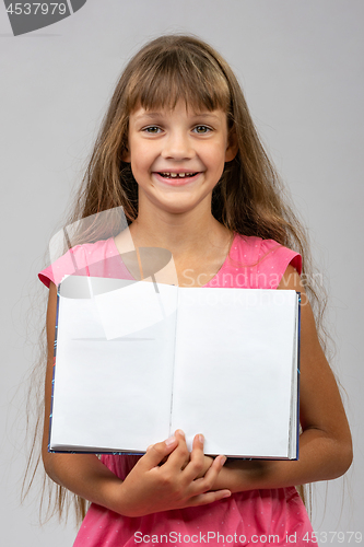 Image of The girl cheerfully shows the opened empty book in her hands