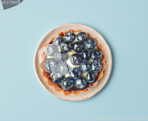 Image of blueberry tart on light blue background