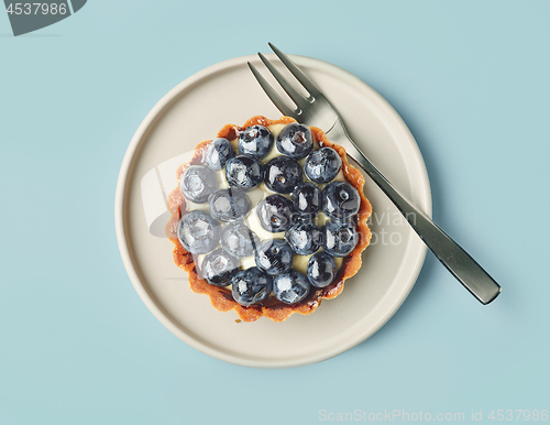 Image of blueberry tart on light blue background