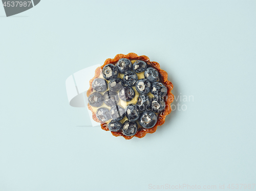 Image of blueberry tart on light blue background