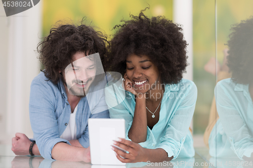Image of Couple relaxing together at home with tablet computer
