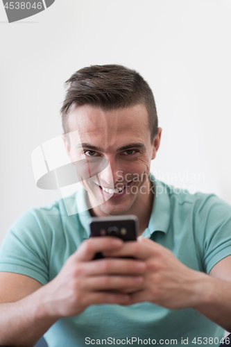 Image of young man using a mobile phone  at home