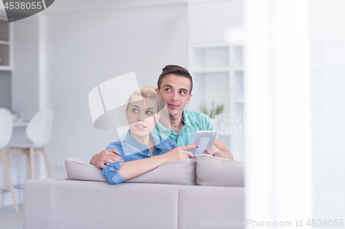 Image of couple relaxing at  home with tablet computers