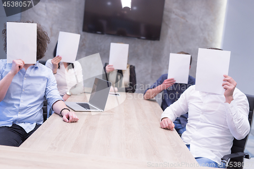 Image of startup business team holding a white paper over face