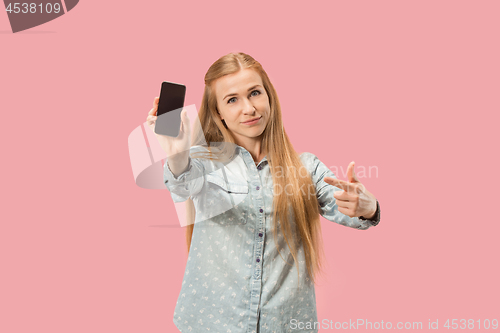 Image of Portrait of a confident casual girl showing blank screen mobile phone isolated over pink background