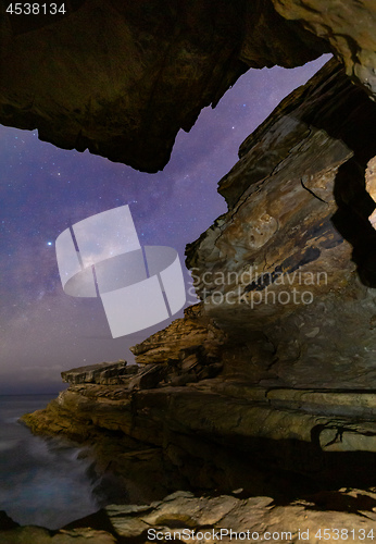 Image of Milky Way viewed through a narrow crack in coastal  rock formati