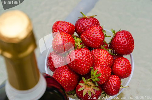 Image of Fresh strawberries and the top of a blurred bottle sparkling win