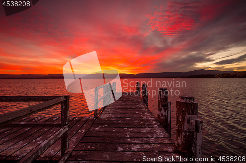 Image of Burning red sunset  on the lake with timber jetty