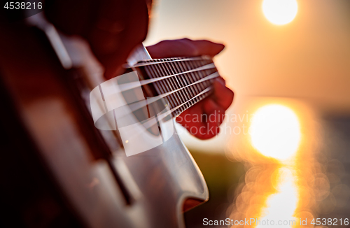 Image of Woman at sunset playing the ukulele