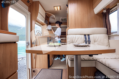 Image of Woman cooking in camper, motorhome interior