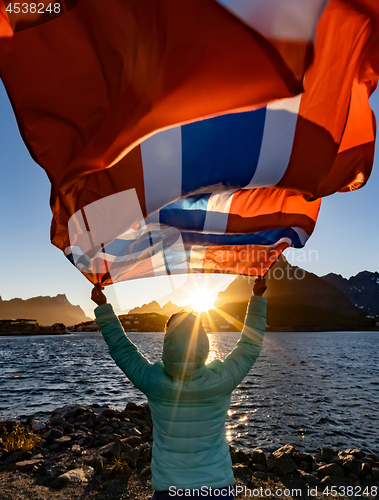 Image of Woman waving the flag of Norway at sunset