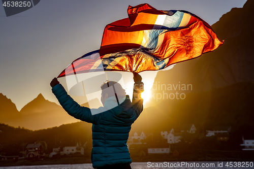 Image of Woman waving the flag of Norway at sunset