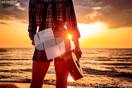 Image of Woman at sunset holding a ukulele