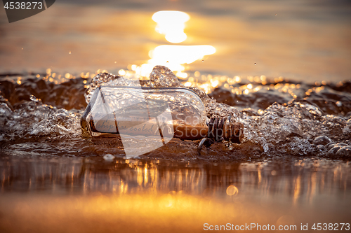 Image of Message in the bottle against the Sun setting down