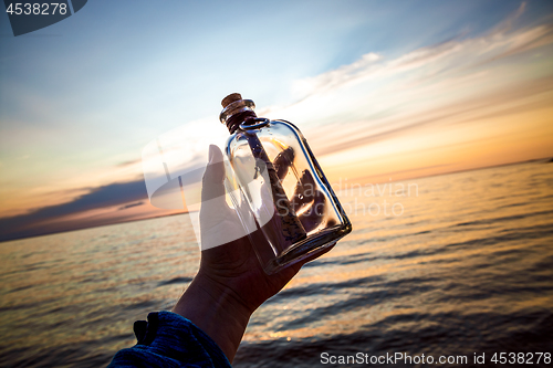 Image of Message in the bottle against the Sun setting down