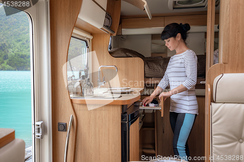 Image of Woman cooking in camper, motorhome interior