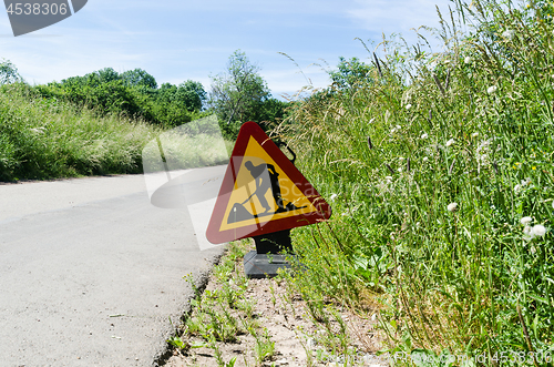 Image of Roadwork sign by roadside among green grass