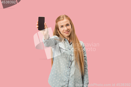 Image of Portrait of a confident casual girl showing blank screen mobile phone isolated over pink background