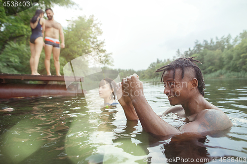 Image of Enjoying river party with friends. Group of beautiful happy young people at the river together