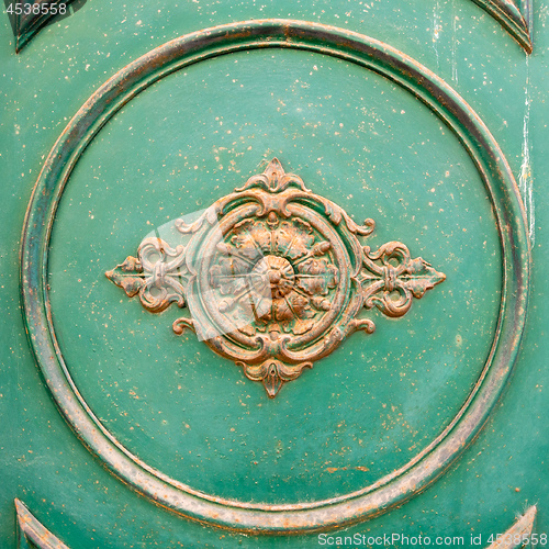 Image of rusty ornamental decoration at a green door in Italy