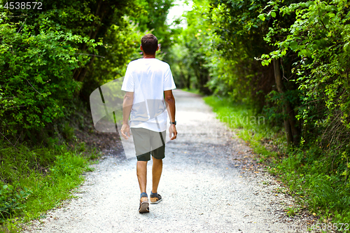 Image of Man walking on path in summer green park. Peaceful atmosphere. R