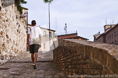 Image of Back view of a man tourist walking in ancient town.