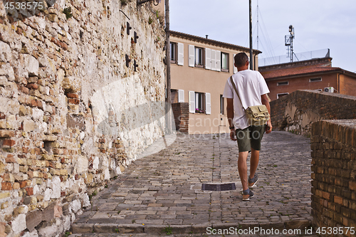 Image of Back view of a man tourist walking in ancient town.