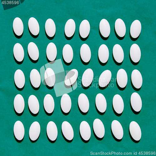 Image of White pills on teal green background.