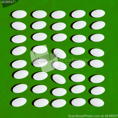 Image of White pills on green background. 