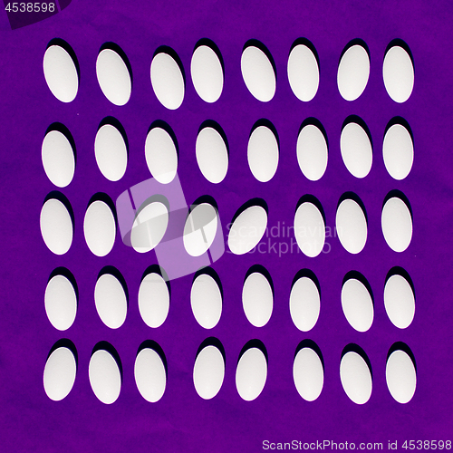 Image of White pills on purple background. 