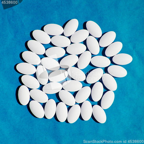 Image of White vitamin pills group on blue background.