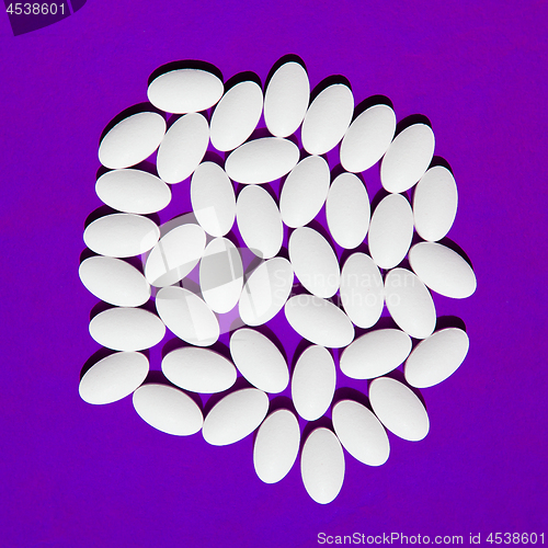 Image of White pills group on purple background.