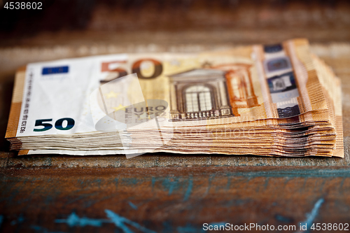 Image of Pile of fifty euro banknotes. Currency notes stacked on wooden t