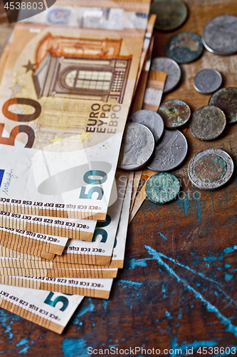 Image of Pile of fifty euro banknotes and ancient coins.